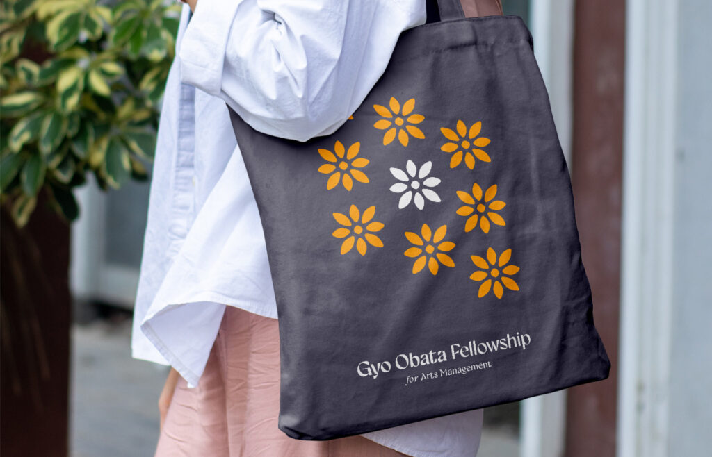 person walking with an well-branded tote bag representing the arts fellowship brand