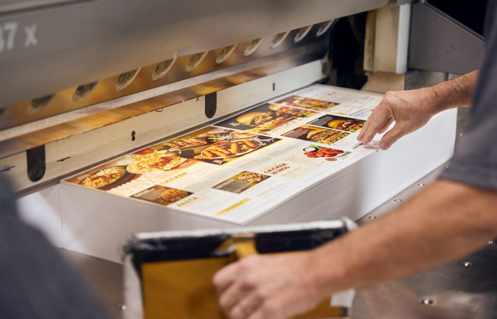 a person placing restaurant menus into a trimming machine