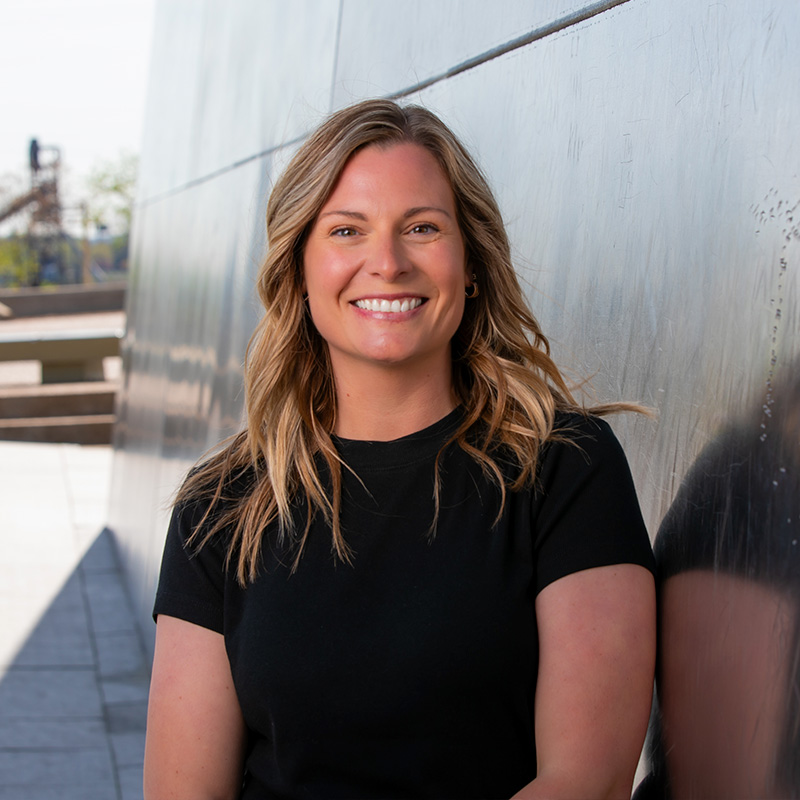 project coordinator smiling and leaning against the st. louis gateway arch